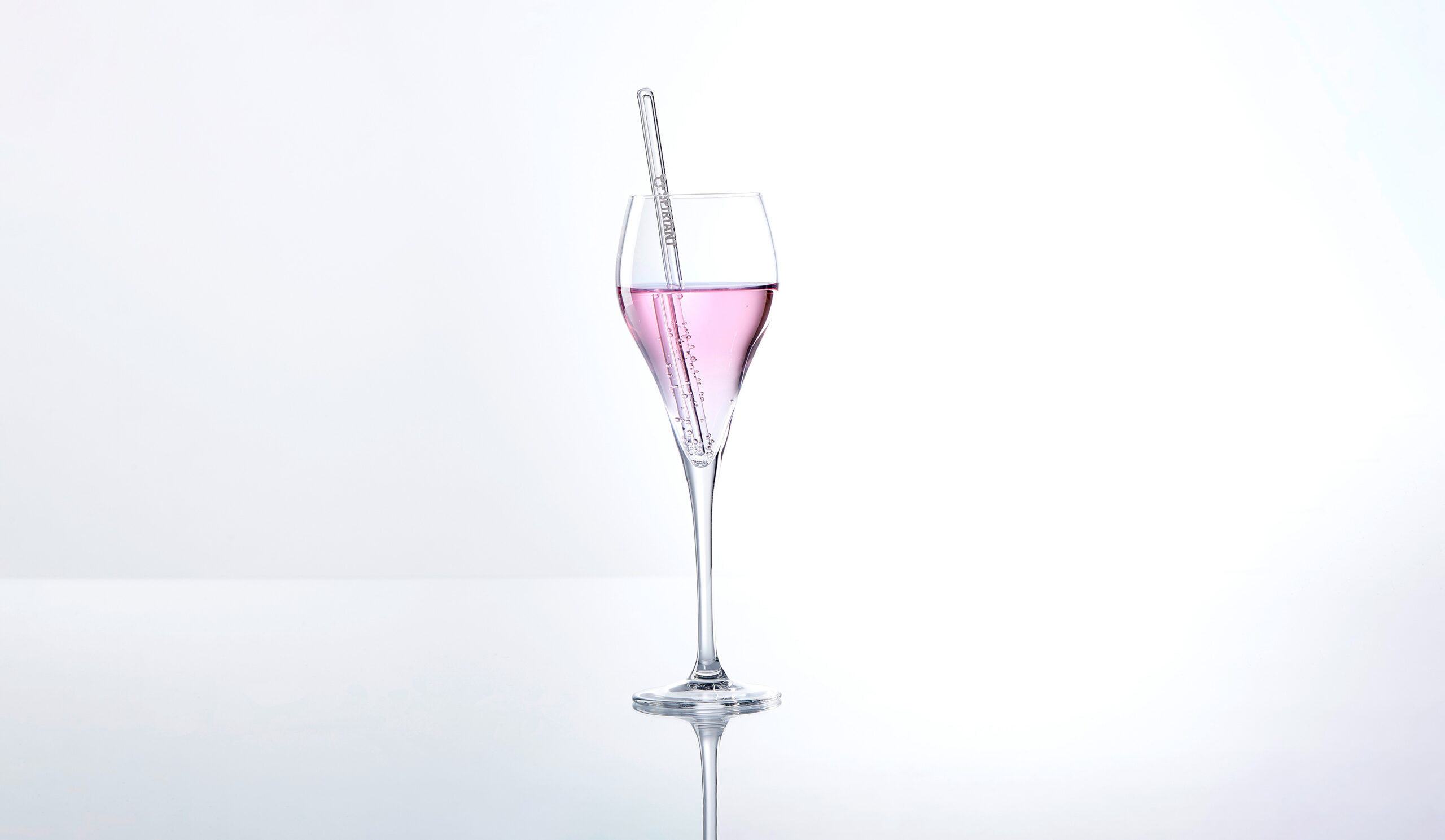 Ein Weinglas mit rosa Flüssigkeit und Glasstrohhalm
